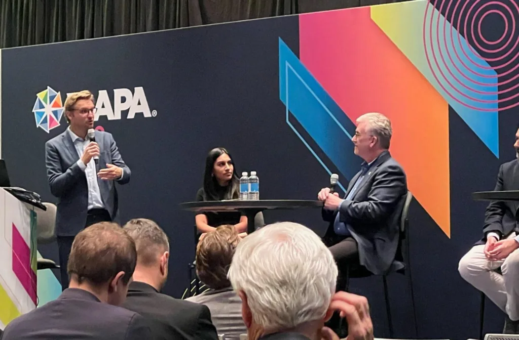 Fireside Chat panel on stage at the IAAPA Expo, with a moderator taking an audience question