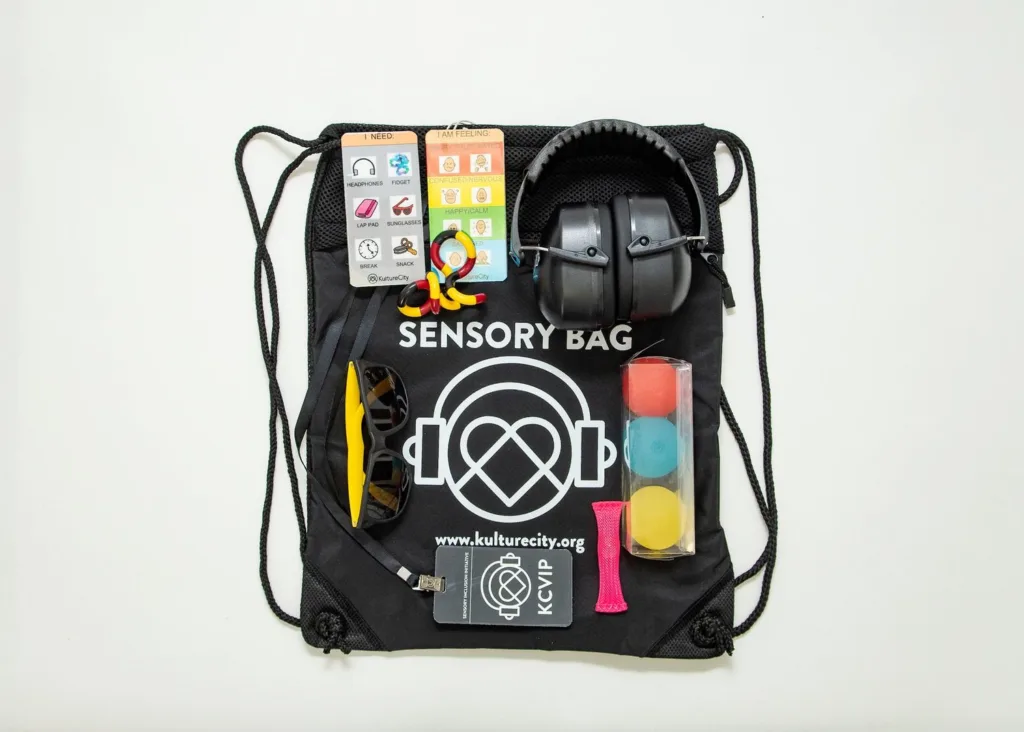 KultureCity sensory bag laid out with headphones, fidget tools and sunglasses