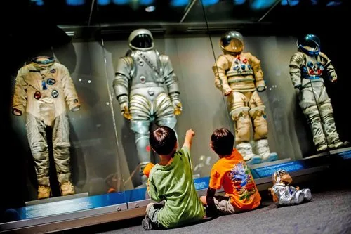 Children sitting on the floor looking up at historic space suits at Kennedy Space Center Visitor Complex