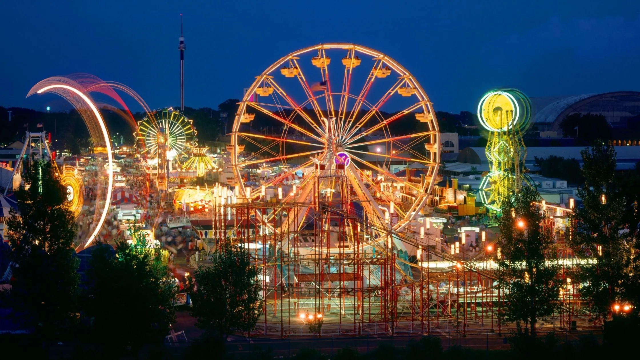 Minnesota State Fair midway rides and Ferris wheel glowing at night