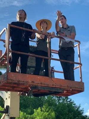 Designers on a raised lift platform reviewing a site from above on a sunny day