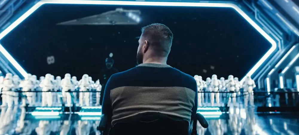 Guest in a wheelchair facing rows of stormtroopers in a Star Wars starship hangar scene at a Disney park