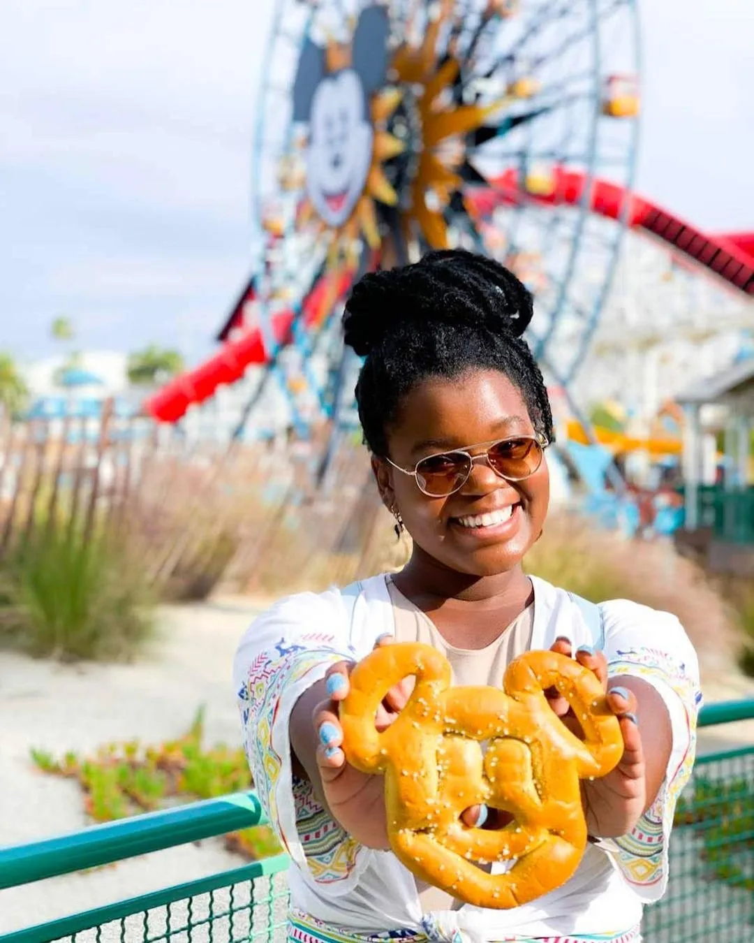 Smiling woman holding a Mickey-shaped pretzel at Disney California Adventure Park, posted by TheDisneyFox