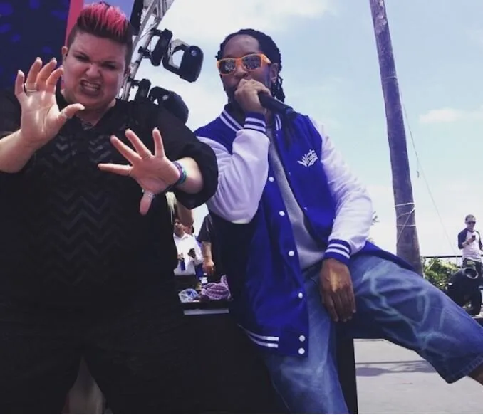 Sign language interpreter performing expressively alongside a rapper at an outdoor concert