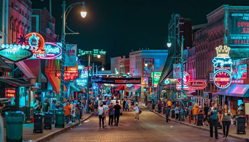 Crowds strolling beneath glowing neon signs on Beale Street in Memphis at night