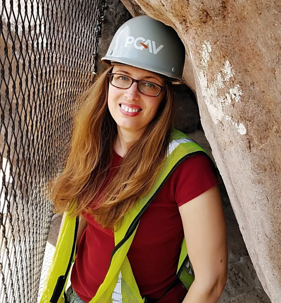 Victoria Gray, PGAV Art Director, in a hard hat and safety vest beside rockwork at El Paso Zoo