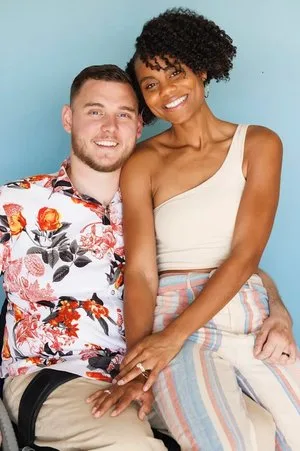 Smiling couple seated close together against a light blue wall