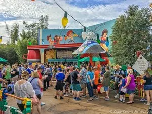 Large crowd queued outside a colorful Toy Story-themed food stand at a Disney park