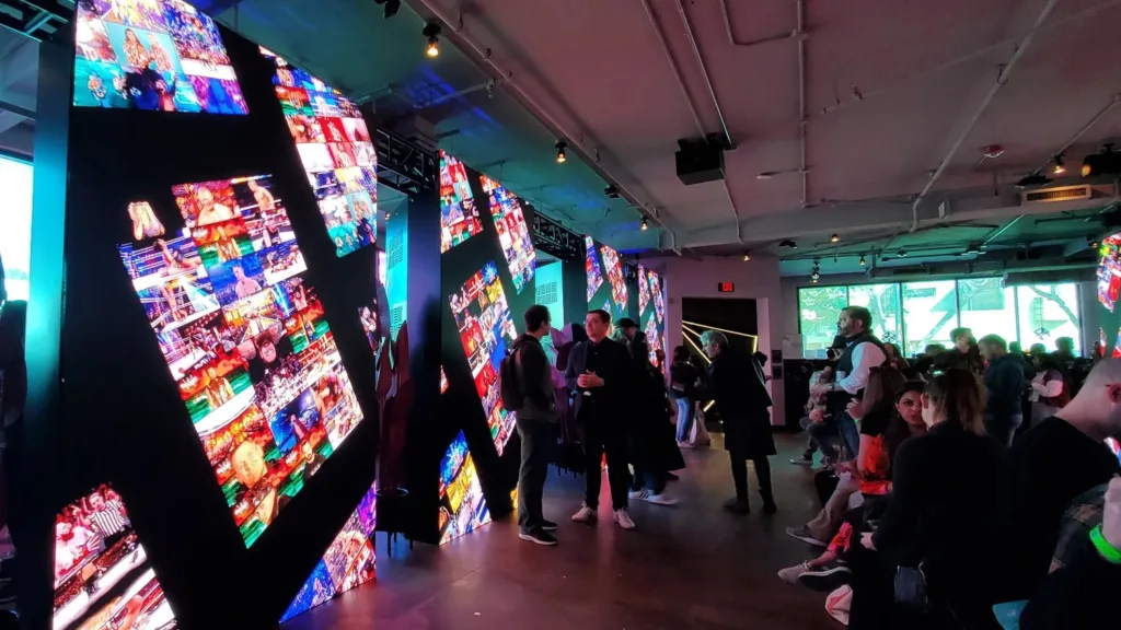 Visitors viewing walls of digital screens at a Blockchain Creative Labs NFT gallery