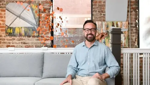 Gary Culbertson seated on a couch in his gallery, Contemporaneo Asheville