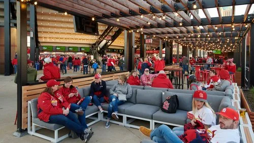 Cardinals fans relaxing on lounge sofas in a covered social space at Busch Stadium