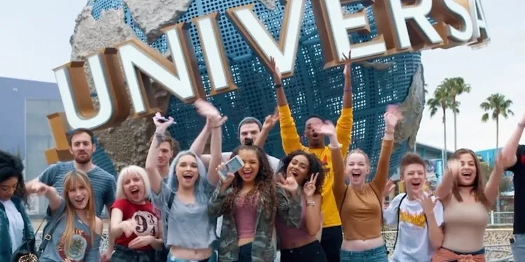 Group of excited teen influencers cheering in front of the Universal globe