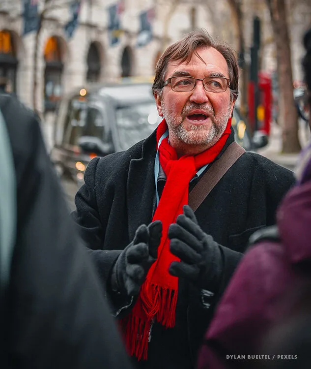 Animated tour guide in a red scarf talking with visitors on a city street