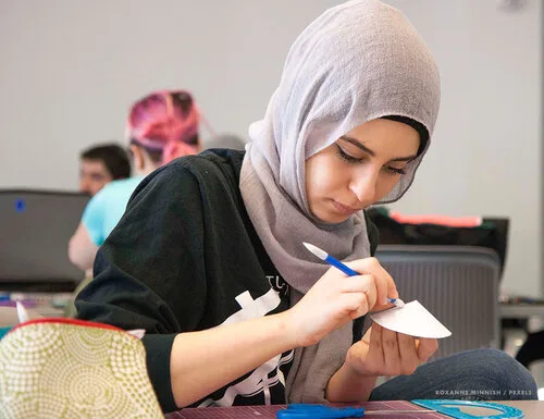 Student carefully drawing on a small object during a hands-on workshop