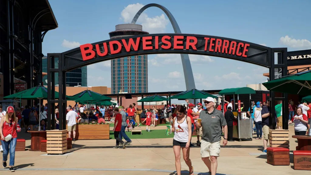Fans walking under the Budweiser Terrace arch at Busch Stadium with the Gateway Arch behind