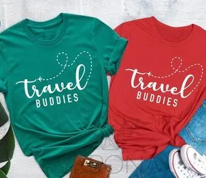Matching green and red Travel Buddies T-shirts laid flat