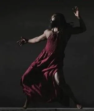 Urban Jazz Dance Company dancer in a flowing red dress performing against a dark backdrop