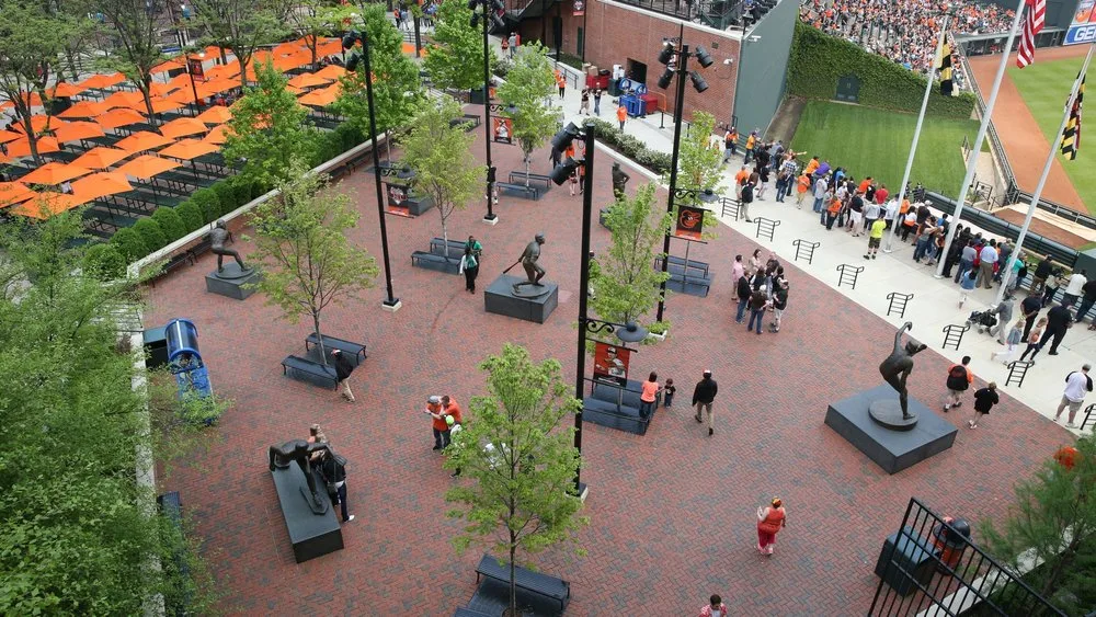 Overhead view of a brick plaza with player statues and trees beside the field at the Orioles ballpark