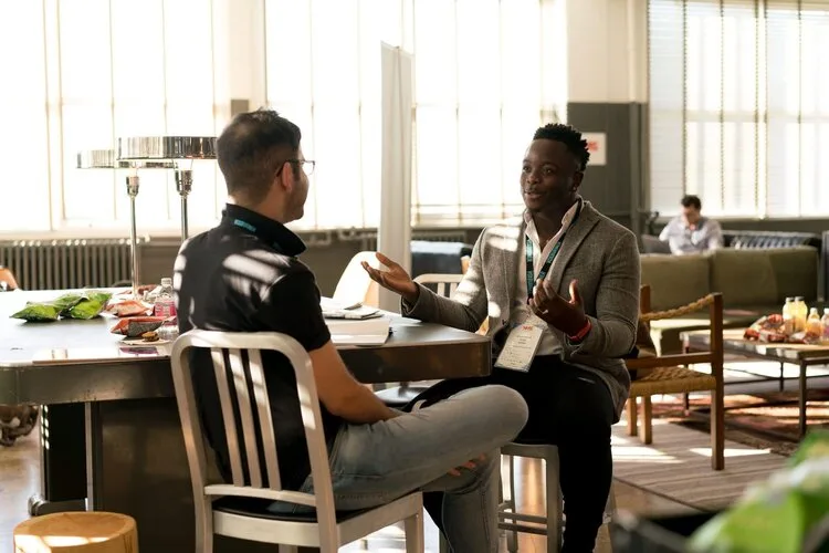 Two colleagues talking at a table in a bright, open office