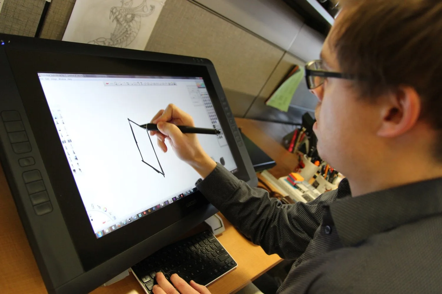 Illustrator sketching on a large pen display tablet at his desk