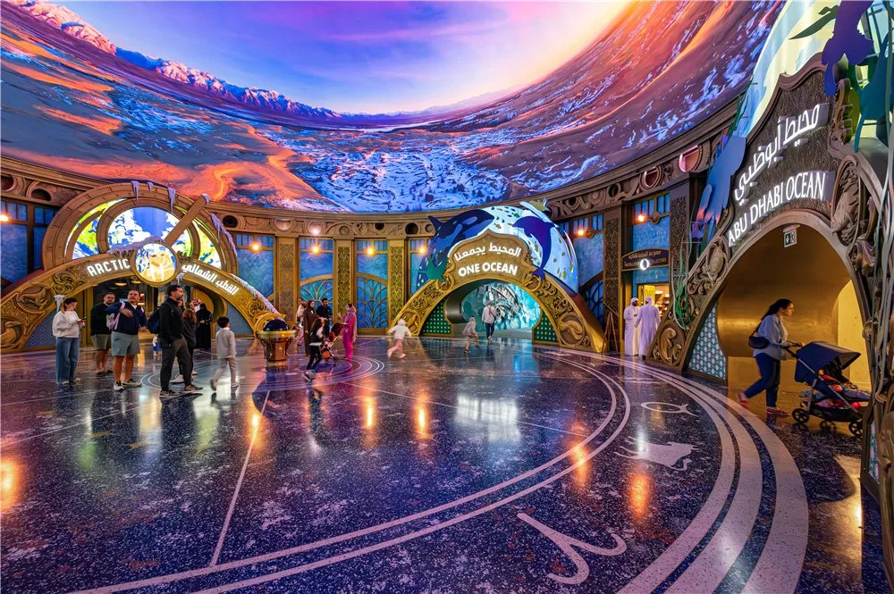 Domed entry hub at SeaWorld Abu Dhabi with a panoramic ocean-and-sky projection and portals to Arctic and One Ocean