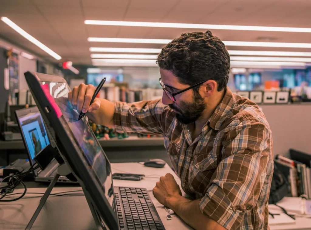PJ Tamayo, PGAV media designer and illustrator, drawing on a pen display at his desk