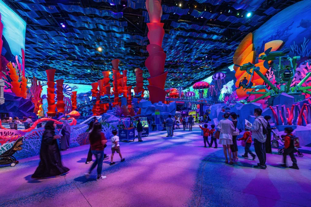 Guests exploring a glowing coral-reef themed realm with giant columns at SeaWorld Abu Dhabi