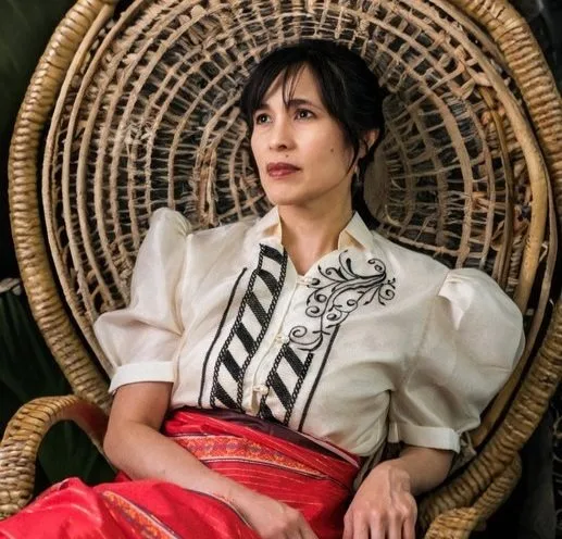 Woman in traditional Filipino attire seated in a wicker peacock chair