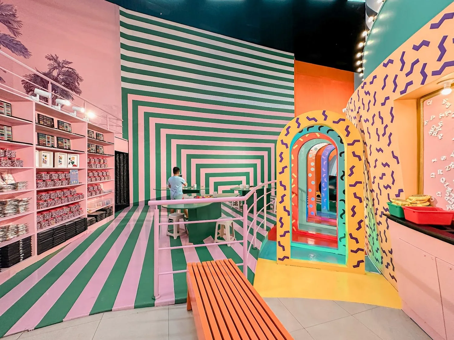 Colorful striped room at the Museum of Emotions in Cebu with pink shelves, patterned arches and a bench