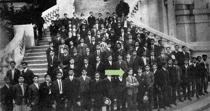 Archival group photo of Filipino pensionado students on steps at the 1904 World's Fair, with an arrow marking one student