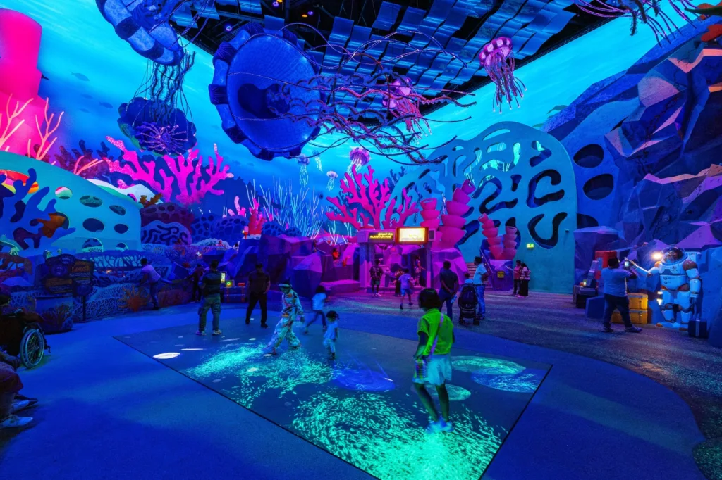Children playing on an interactive glowing floor in the MicroOcean realm at SeaWorld Yas Island
