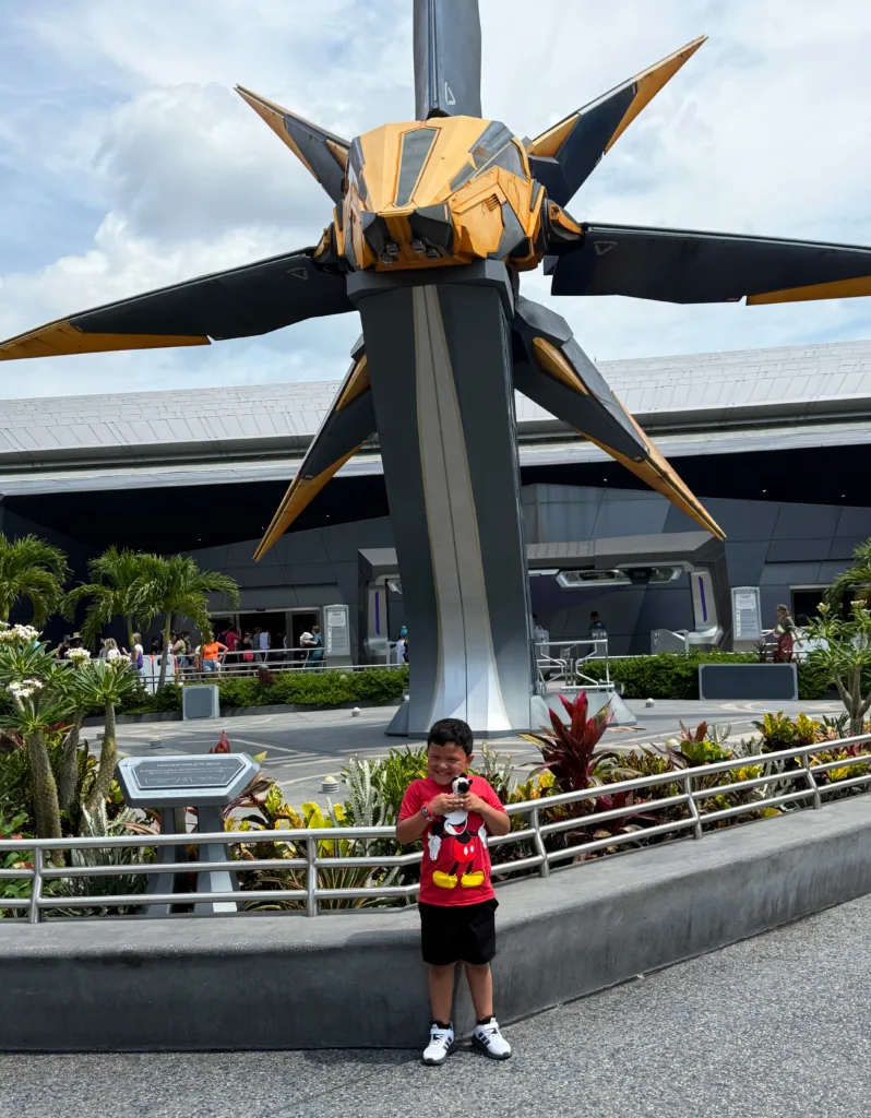 Child posing before the Guardians of the Galaxy spaceship sculpture at EPCOT, Walt Disney World