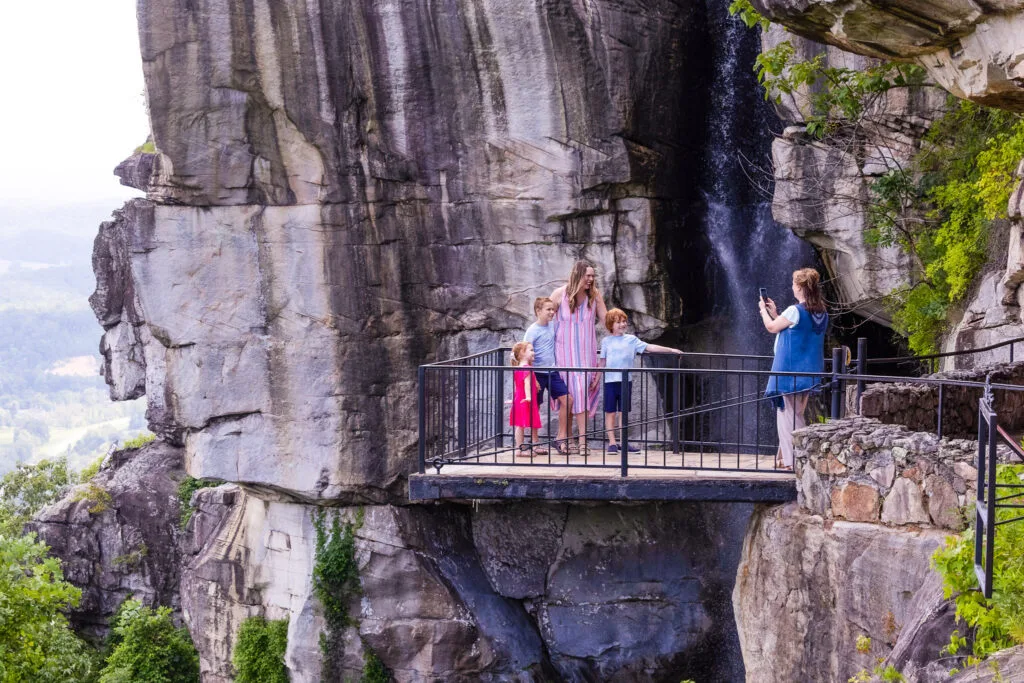 Family on an overlook platform beside a waterfall and towering rock cliffs at Rock City, Lookout Mountain