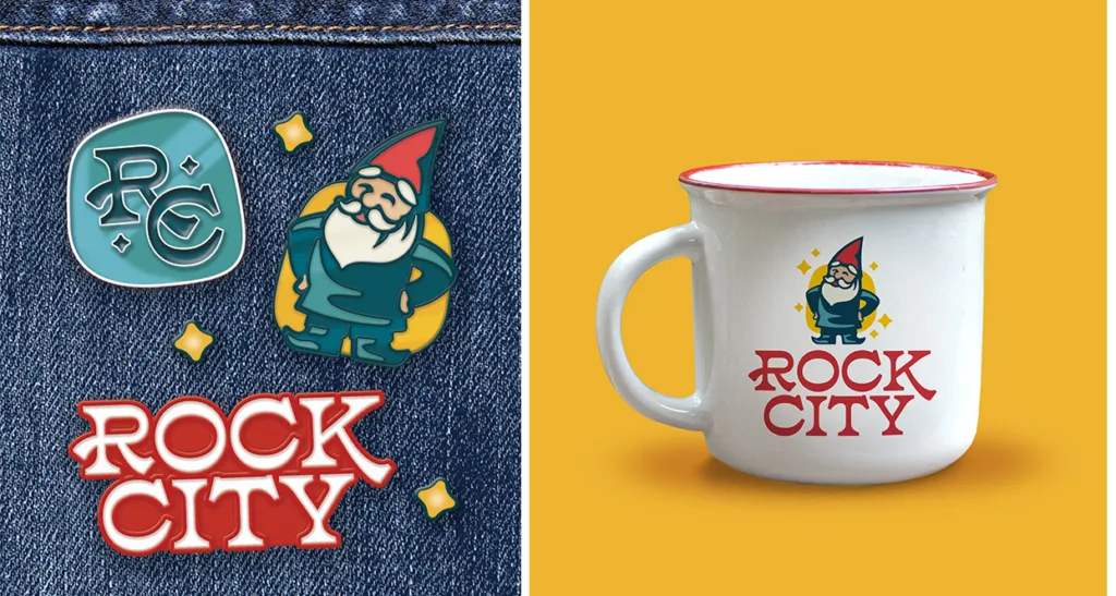 Rock City enamel pins on denim beside a white camp mug printed with the new gnome logo