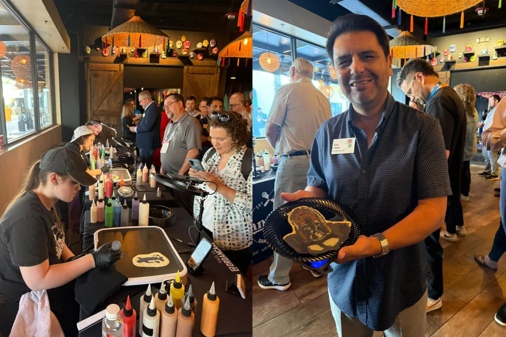 Pancake artist drawing on a griddle and a guest holding a pancake portrait at the PGAV IAAPA breakfast