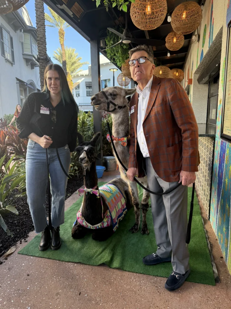 Two guests posing with a llama at the PGAV pancake breakfast