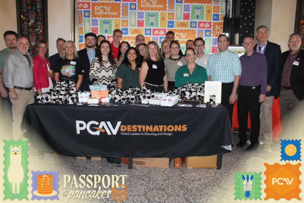 PGAV Destinations team group photo behind a swag table at the Passport to Pancakes IAAPA client breakfast