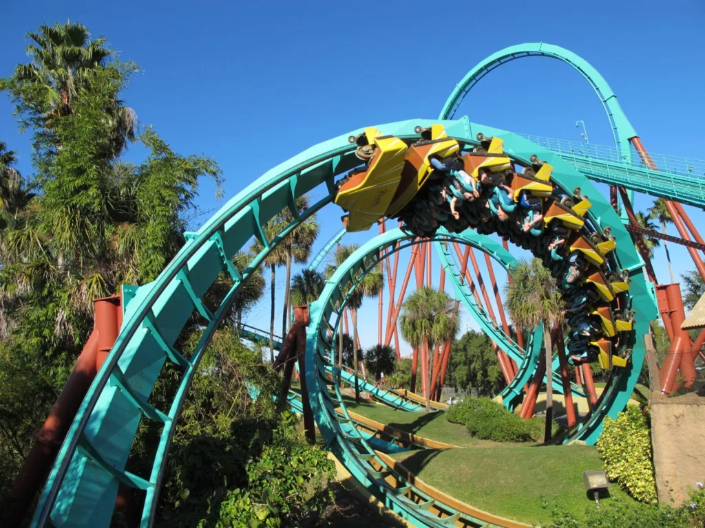 Riders on Kumba's teal corkscrew track surrounded by palms at Busch Gardens Tampa