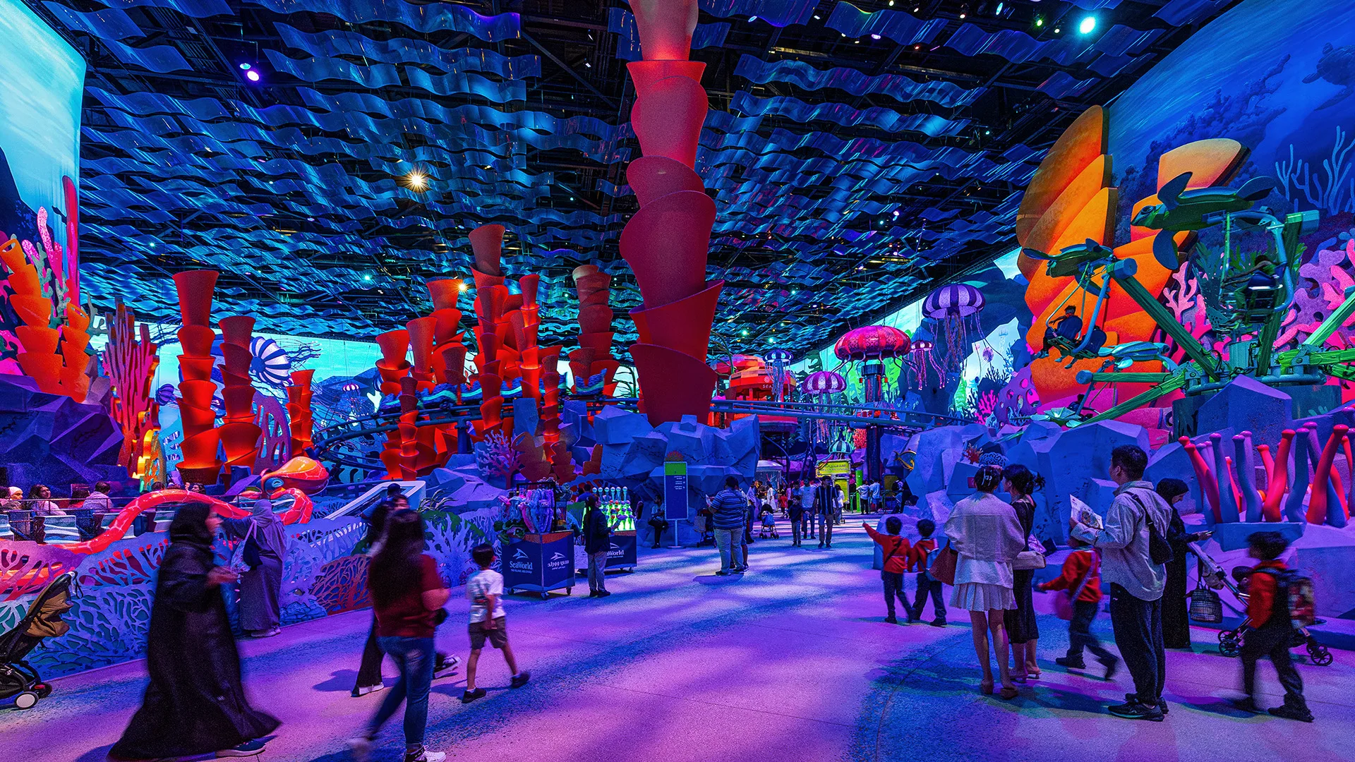 Guests exploring a vivid purple and blue undersea-themed gallery with towering coral forms at SeaWorld Abu Dhabi