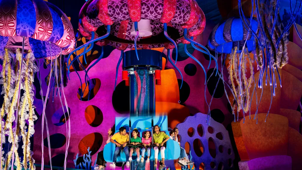 Family riding Jelly Plunge beneath glowing jellyfish sculptures at SeaWorld Yas Island, Abu Dhabi