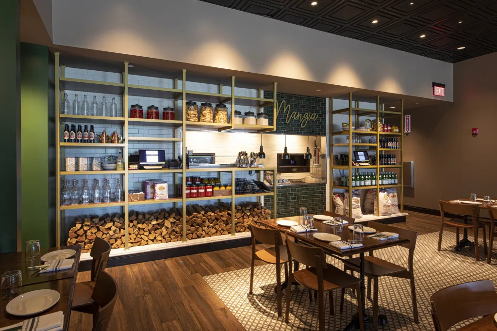 Piccolo Buco dining room with open shelving of wine, pantry goods and stacked firewood