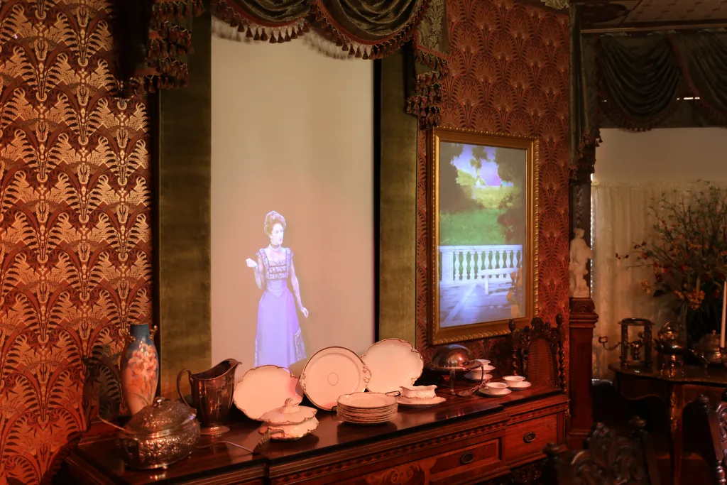 Projected woman in period dress appears in the Victorian dining room of the restored Schifferdecker home