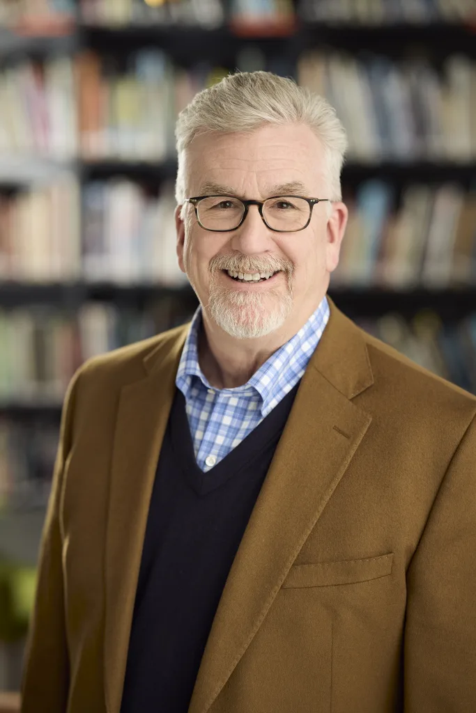 Portrait of Mike Konzen, PGAV Destinations leader, smiling in front of bookshelves