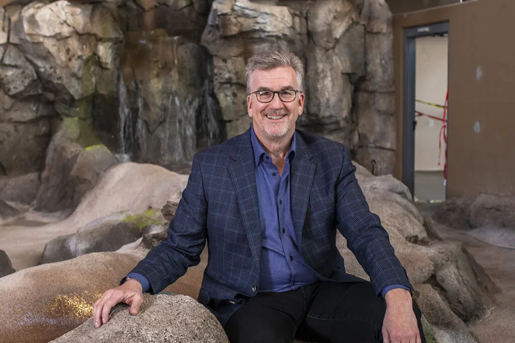 Mike Konzen seated on themed rockwork inside an exhibit under construction